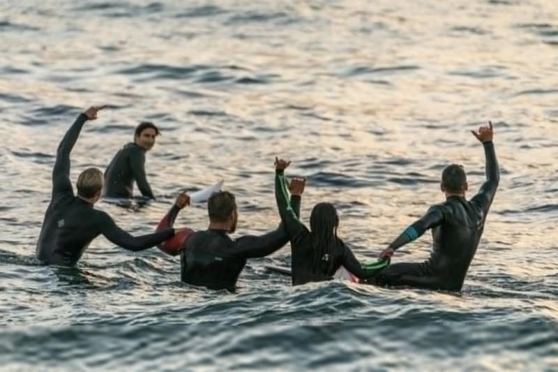 Friends in wetsuits cheering in the water