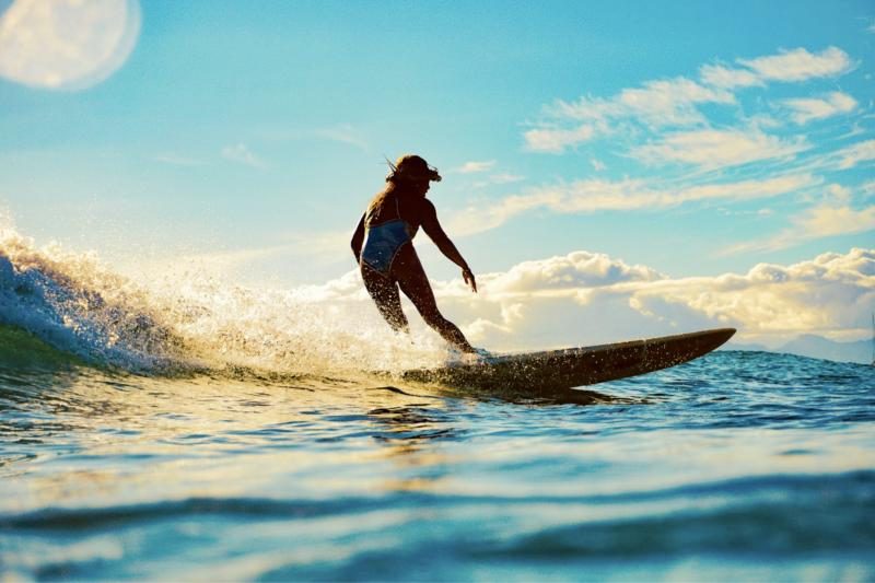 A surfer rides a wave at golden hour